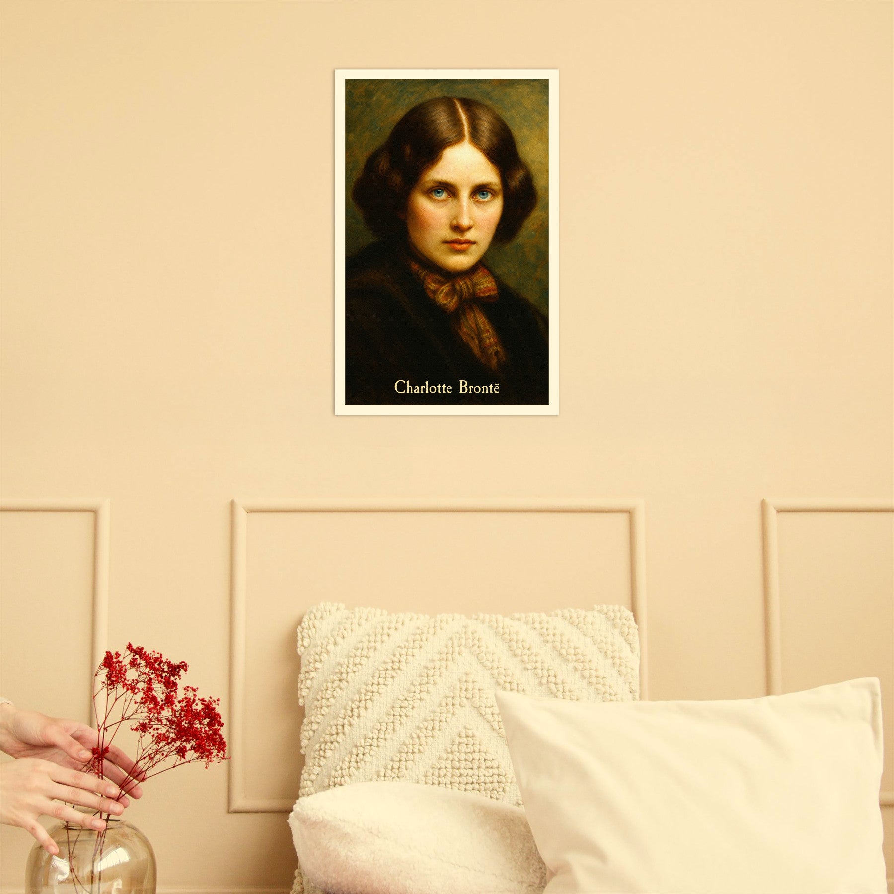 Portrait of Charlotte Bronte on a wall above a bed with pillows and a vase of red flowers.