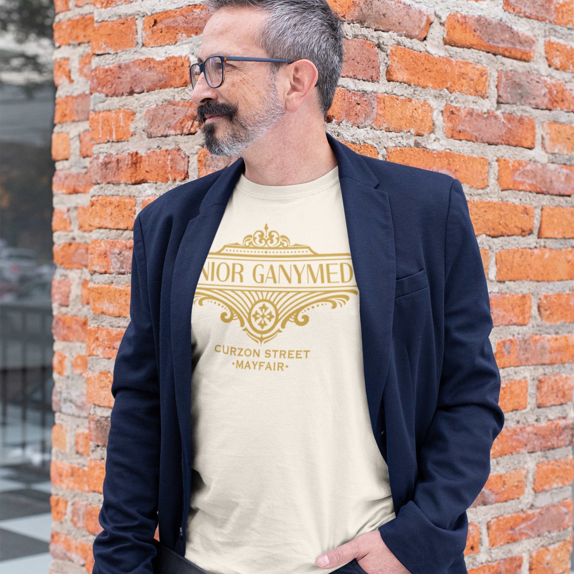 Man wearing a vintage white color P.G. Wodehouse t-shirt with gold Jeeves text against a brick wall